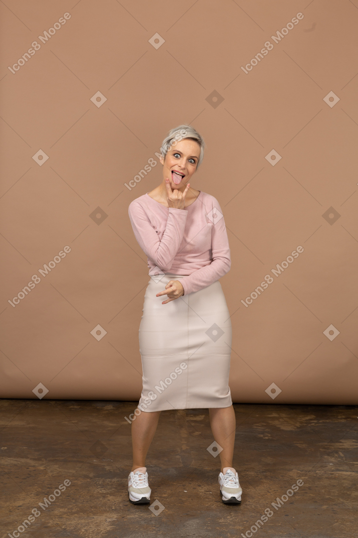 Vue de face d'une femme heureuse dans des vêtements décontractés montrant la langue