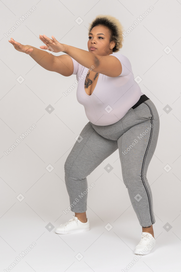 Regordeta mujer negra en cuclillas con los brazos extendidos