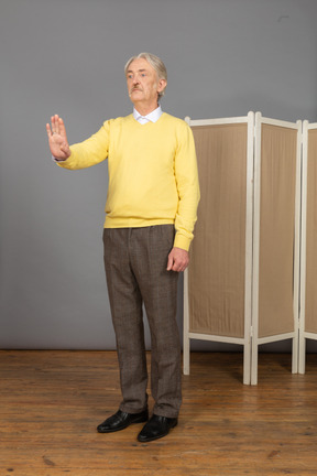 Vista di tre quarti di un uomo anziano che alza la mano