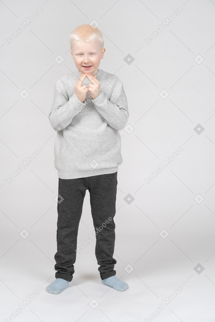 Kleiner junge, der mit seinen fingern dreiecksform macht