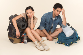 Jovem casal interracial sentado perto de mochilas enormes