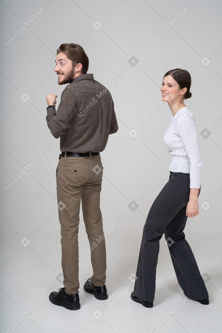 Vista posteriore di tre quarti di una giovane coppia sorridente felice in abiti da ufficio