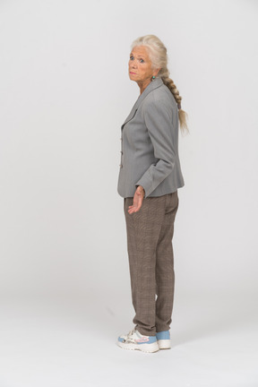 Rear view of an old lady in suit looking at someone and gesturing