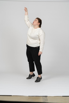 Vista frontale di una donna plus size in abiti casual in piedi con il braccio alzato