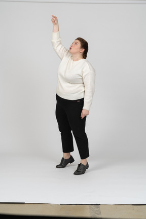 Front view of a plus size woman in casual clothes standing with raised arm