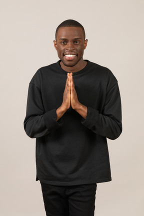 Smiling young man putting hands together