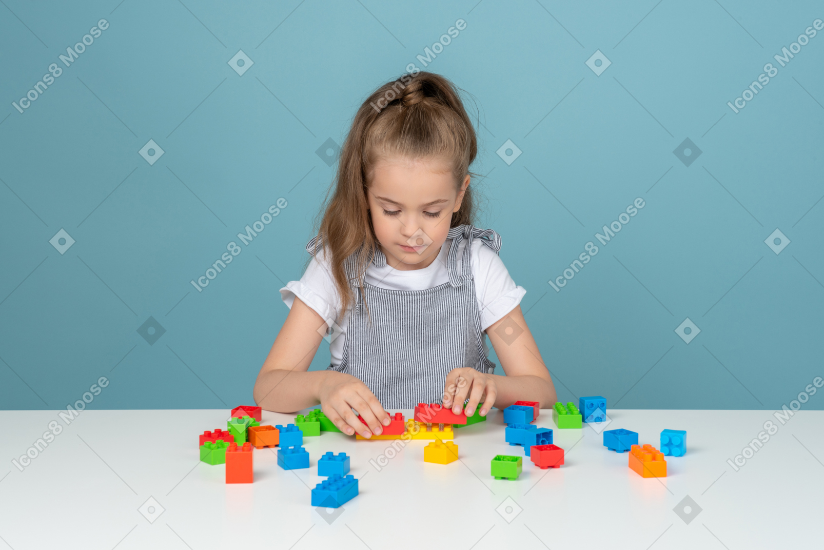 Focused little girl playing with building blocks
