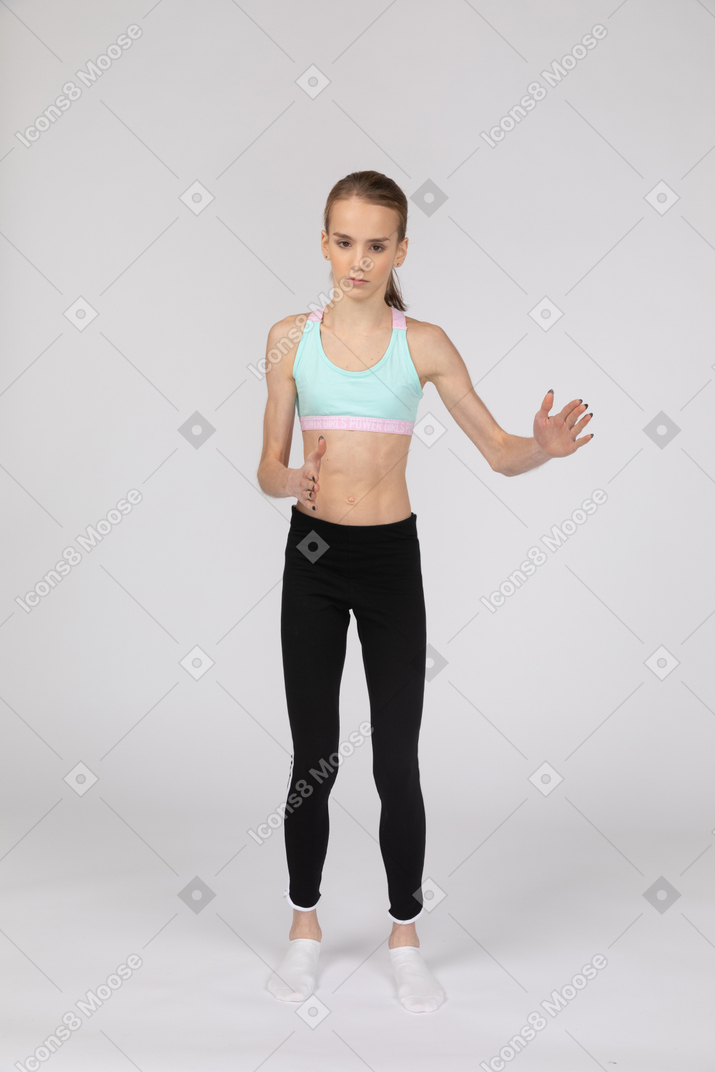 Front view of a teen girl in sportswear standing like a robot