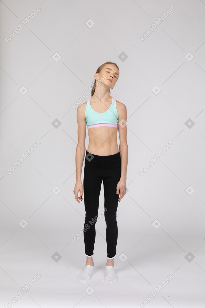 Vista frontal de uma adolescente em roupas esportivas inclinando a cabeça
