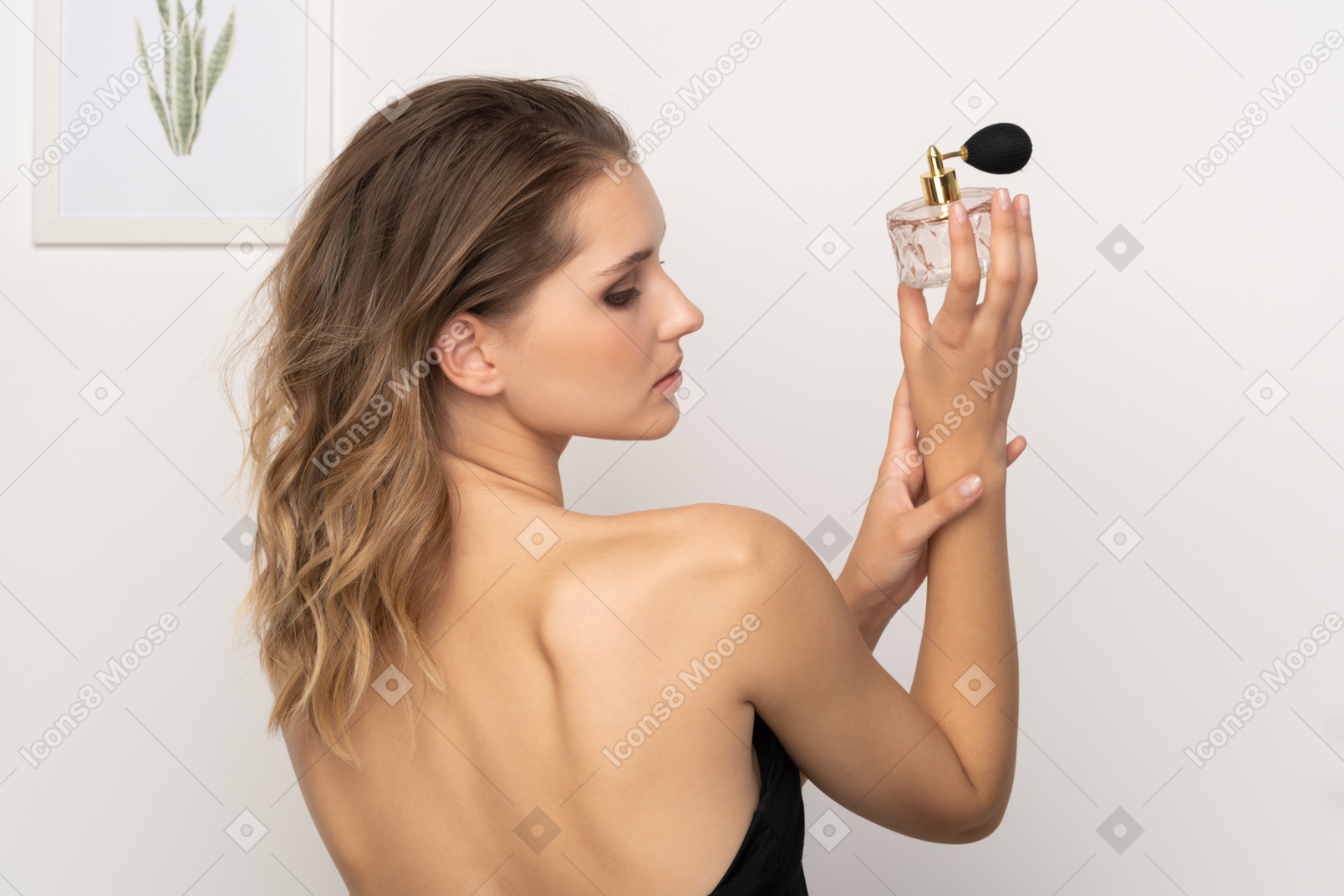 一个性感的年轻女子拿着一瓶香水的背影