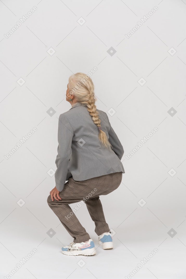 Back view of an old lady in suit squatting
