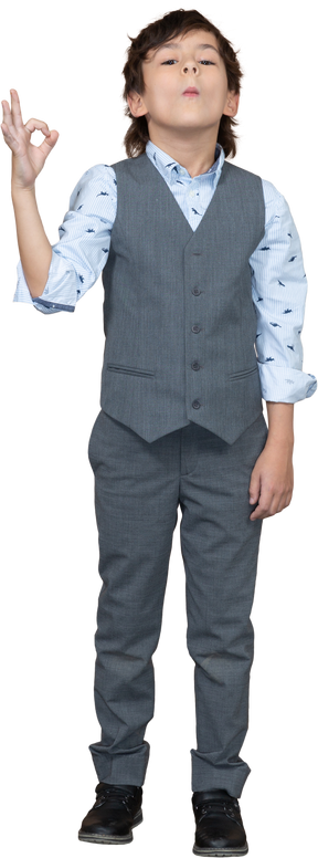 Vista frontale di un ragazzo in abito grigio che mostra segno ok