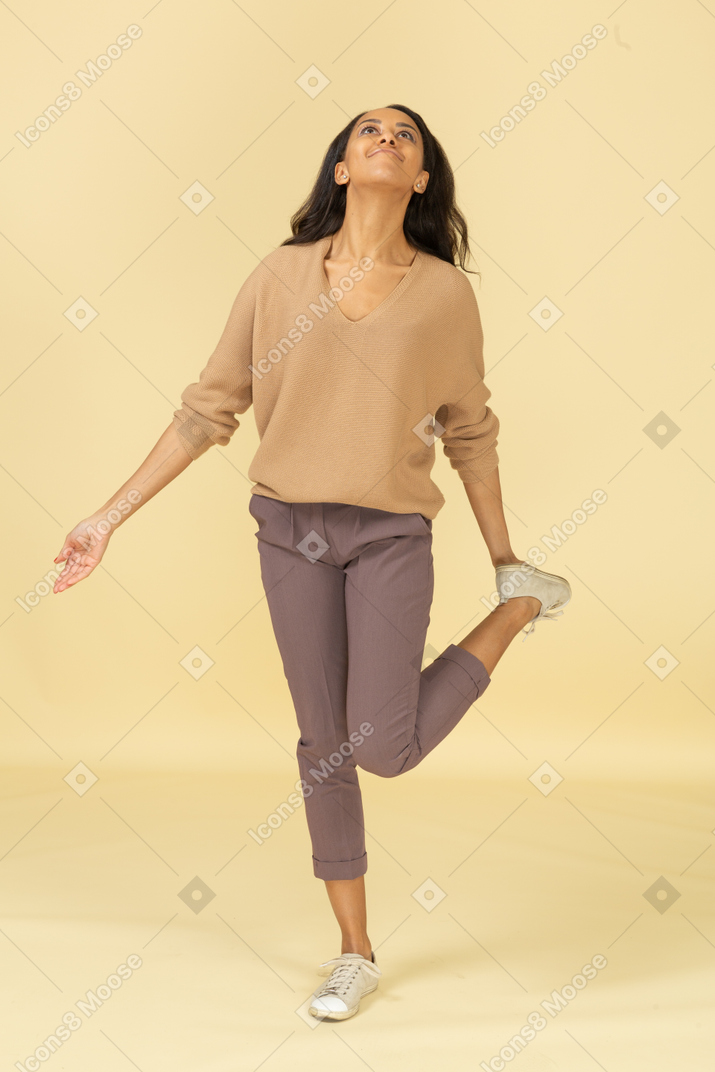 Vista frontal de uma jovem mulher de pele escura tocando seu tornozelo