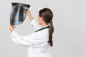 Young female doctor looking attentively on x-ray photograph