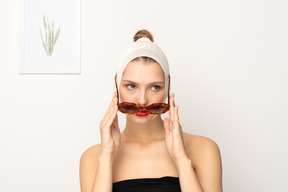 Femme avec un bandage sur la tête enlevant des lunettes de soleil