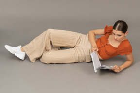 Young woman lying down with book