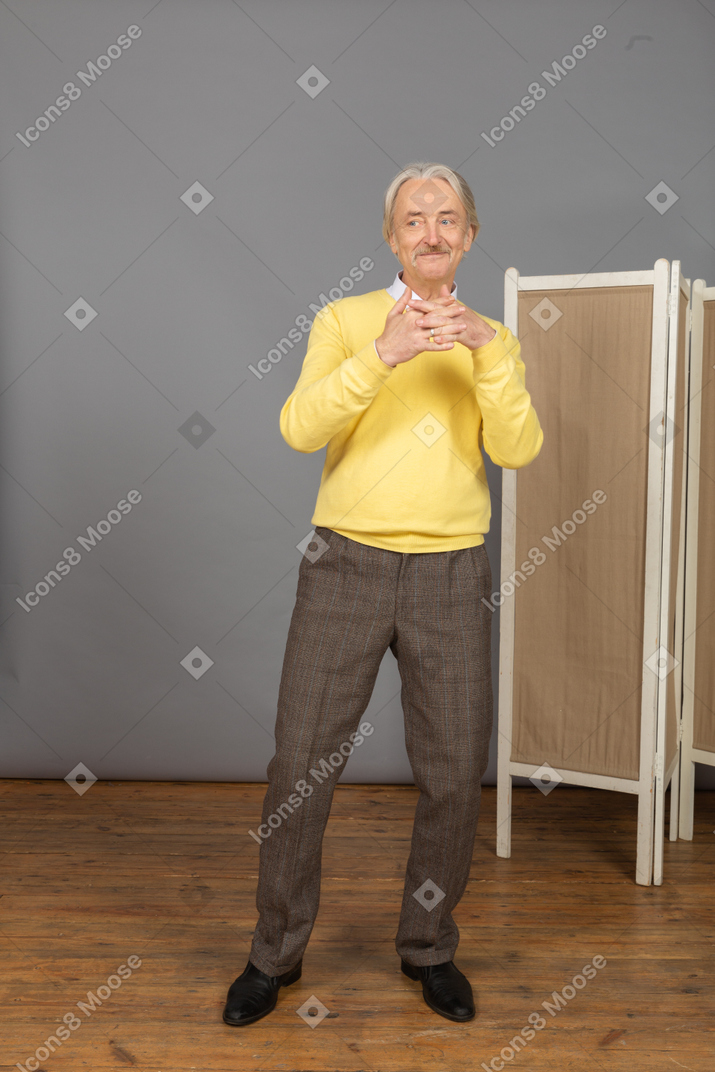 Vista frontal de un anciano sonriente juntando las manos