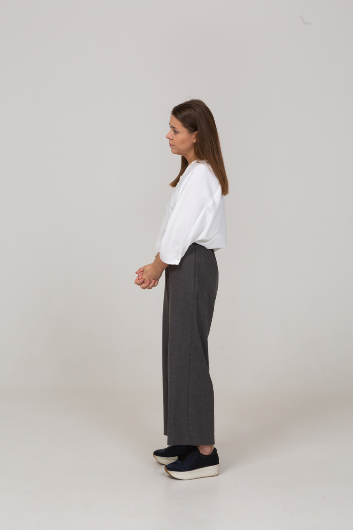 Side view of a sad young lady in office clothing holding hands together