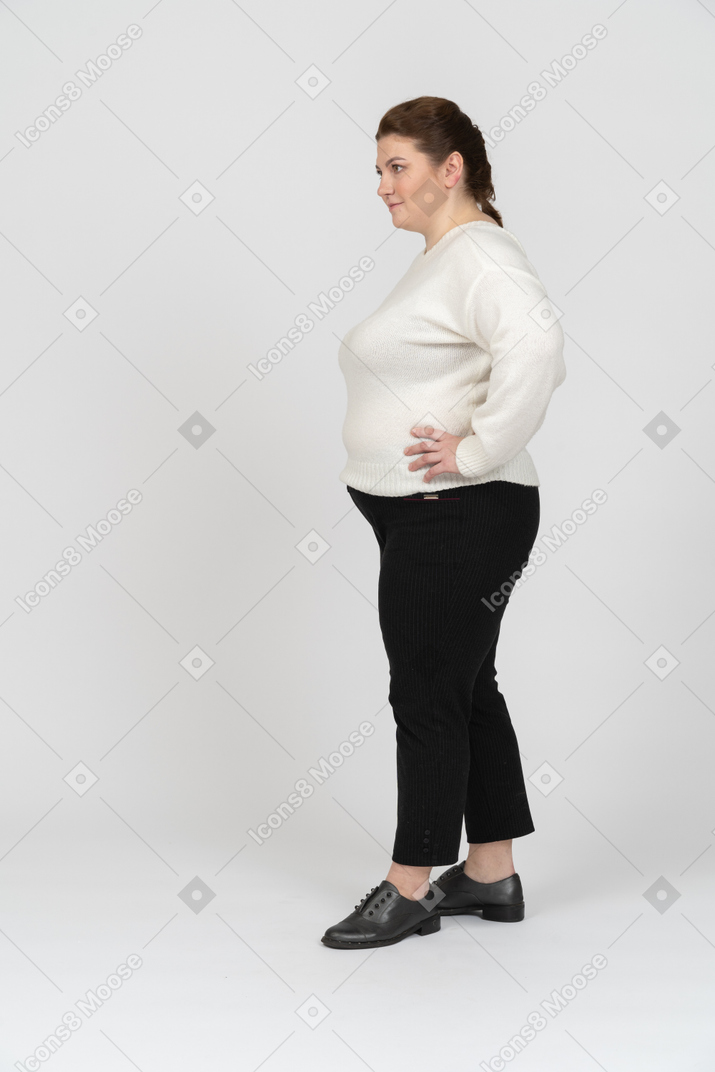 Plus size woman in white sweater standing with hands on hips