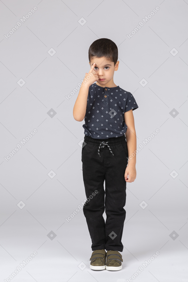 Vista frontal de um menino fofo em roupas casuais apontando para a testa