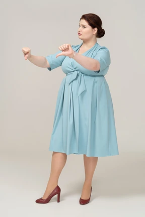 Front view of a woman in blue dress showing thumbs down