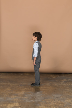 プロファイルに立っている灰色のスーツの少年