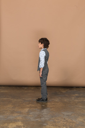 Boy in grey suit standing in profile