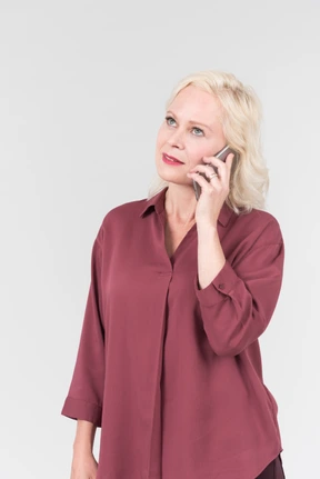A nice-looking middle-aged blonde woman in a burgundy shirt talking by the phone