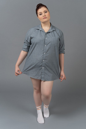 Donna taglie forti in posa in camicia oversize su sfondo grigio