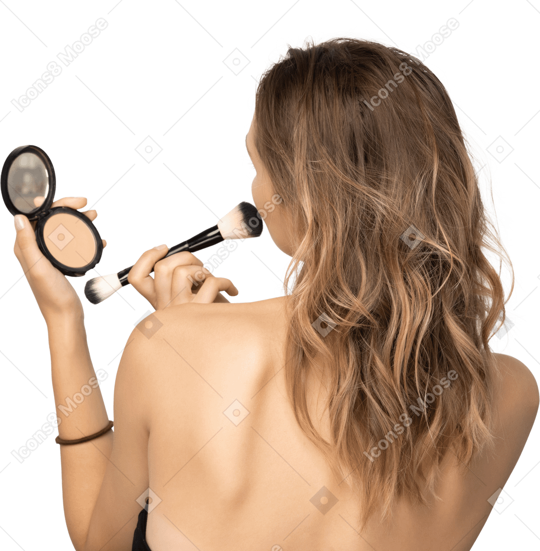 Back view of a young woman applying face powder while holding a mirror