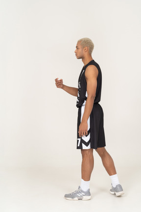 一个年轻的男篮球运动员指着自己的侧视图