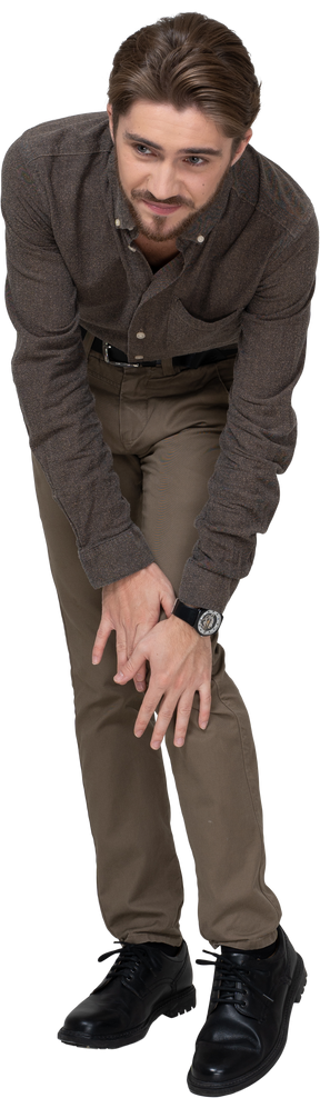 Vista frontal de um jovem com roupas de escritório tocando o joelho