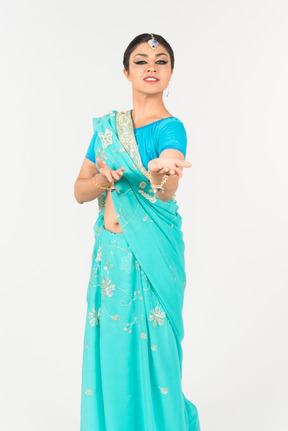 Jovem mulher indiana em pé de sari azul em posição de dança