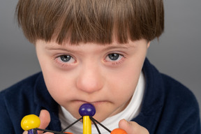 彼の手におもちゃでカメラを見て悲しい小さな男の子