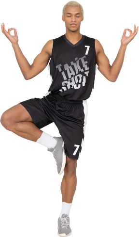 Вид спереди медитирующего молодого баскетболиста, показывающего средние пальцы