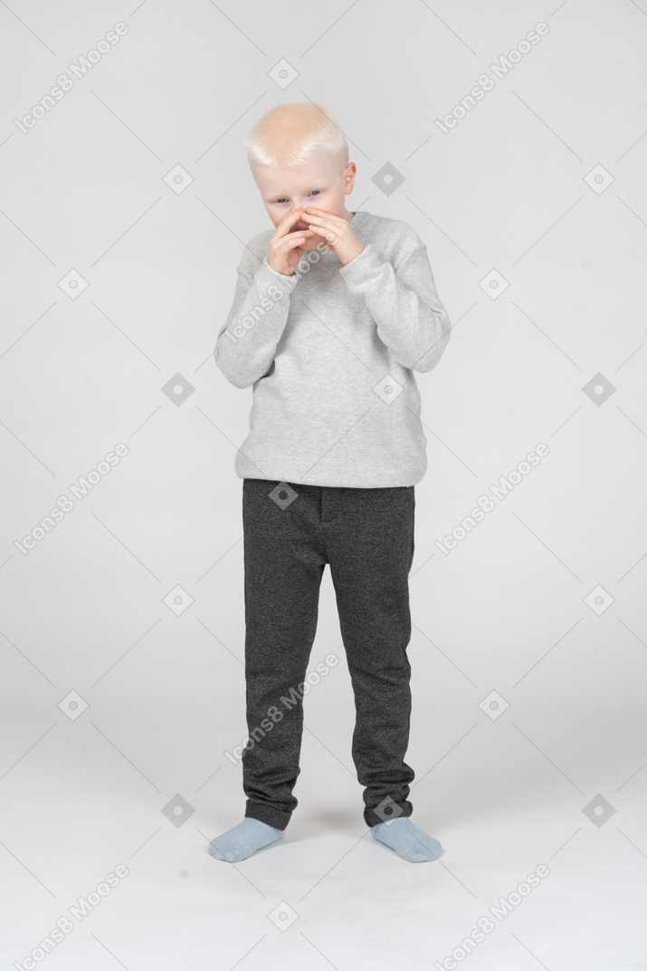 Vista frontale di un ragazzo che copre la bocca con le mani