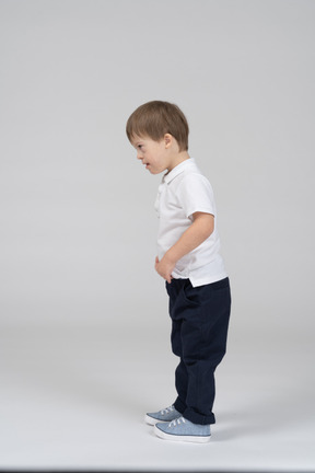 Vista lateral del niño de pie con las manos en el estómago
