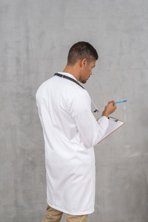 Vista traseira do médico fazendo anotações no prontuário médico
