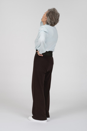 Vista posteriore di tre quarti di una donna anziana che inclina la testa all'indietro
