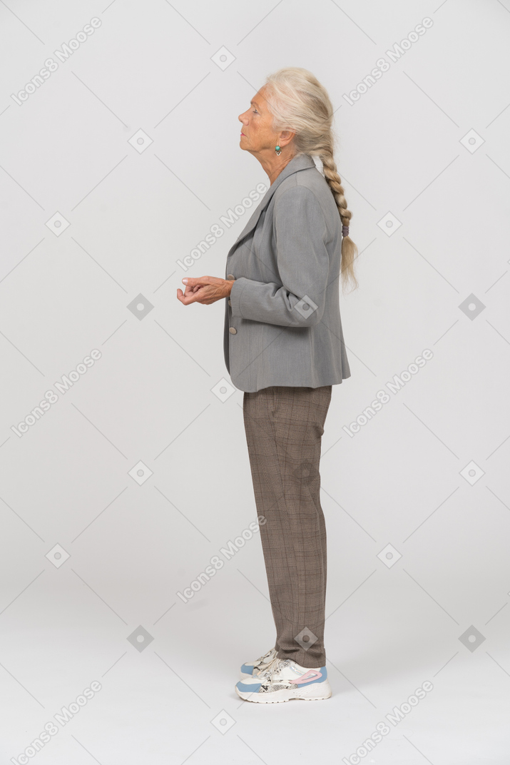 Old woman in suit standing in profile and looking up
