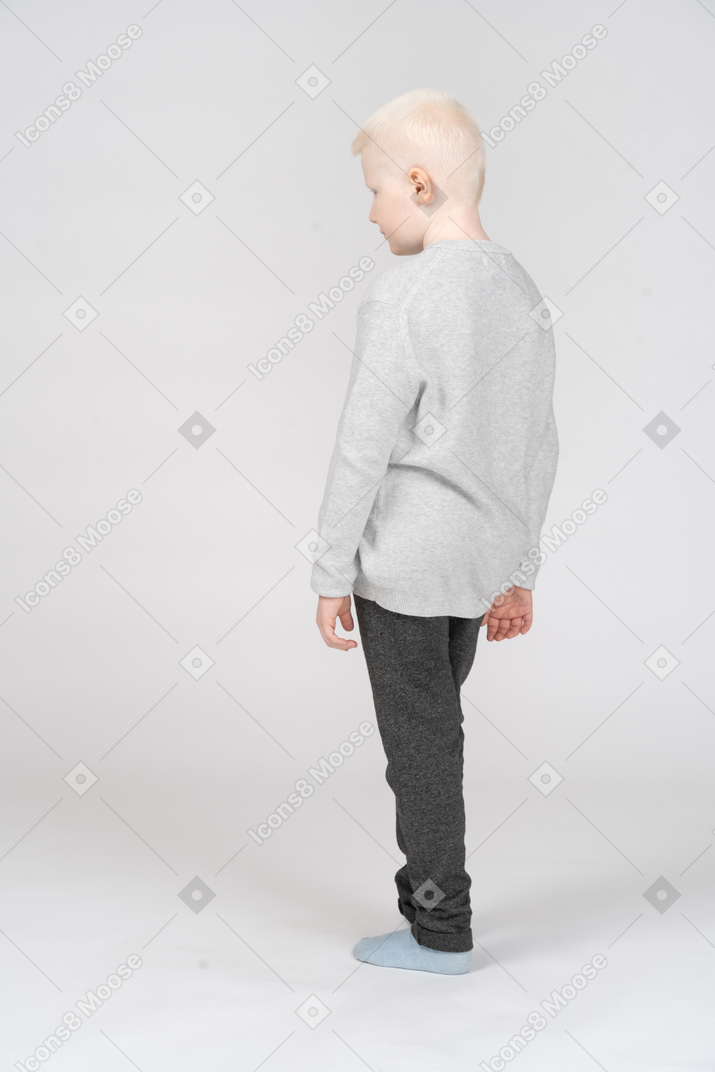 Vista traseira de um garotinho loiro de pé sozinho