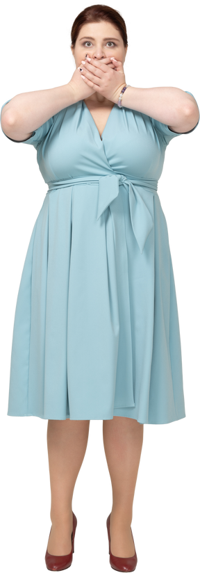 Vista frontal de una mujer en vestido azul cubriendo la boca con las manos
