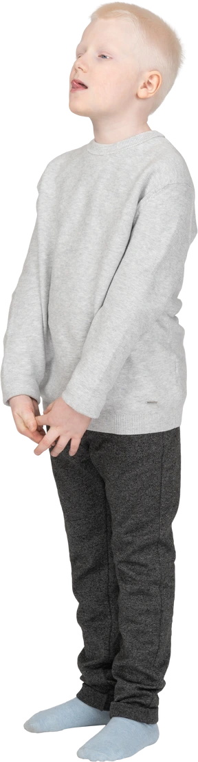 Three-quarters view of a kid boy putting hands together and showing tongue