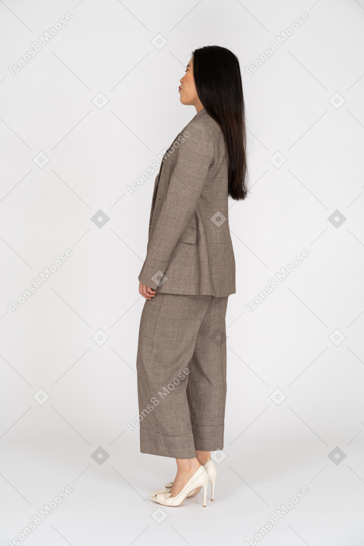 Three-quarter back view of a pouting young lady in brown business suit closing her eyes