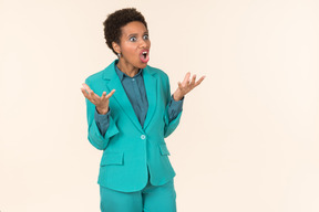 Black woman with a short haircut, wearing all blue, standing against a plain pastel background, looking emotional