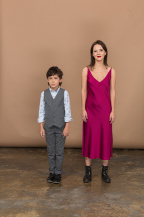 Mulher de vestido vermelho em pé com um menino sorridente