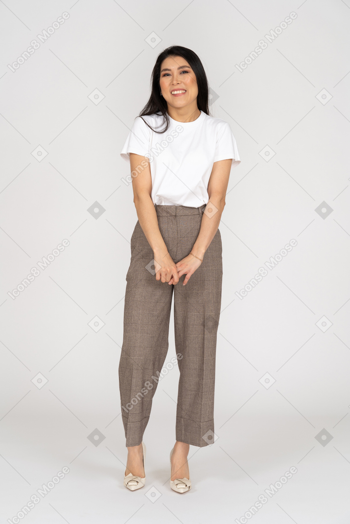 Front view of a shy smiling young lady in breeches and t-shirt holding hands together