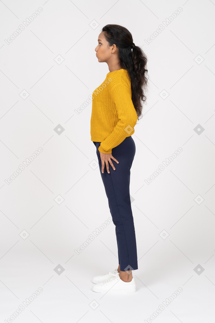 Side view of a girl in casual clothes standing with hand on hip