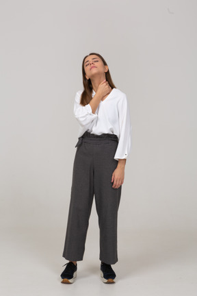 Front view of a young lady in office clothing touching neck