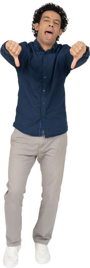 Vista frontal de un hombre en ropa casual mostrando los pulgares hacia abajo